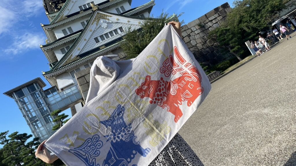 大阪城の前で虎狼来くじのタオルを掲げて撮った写真です。